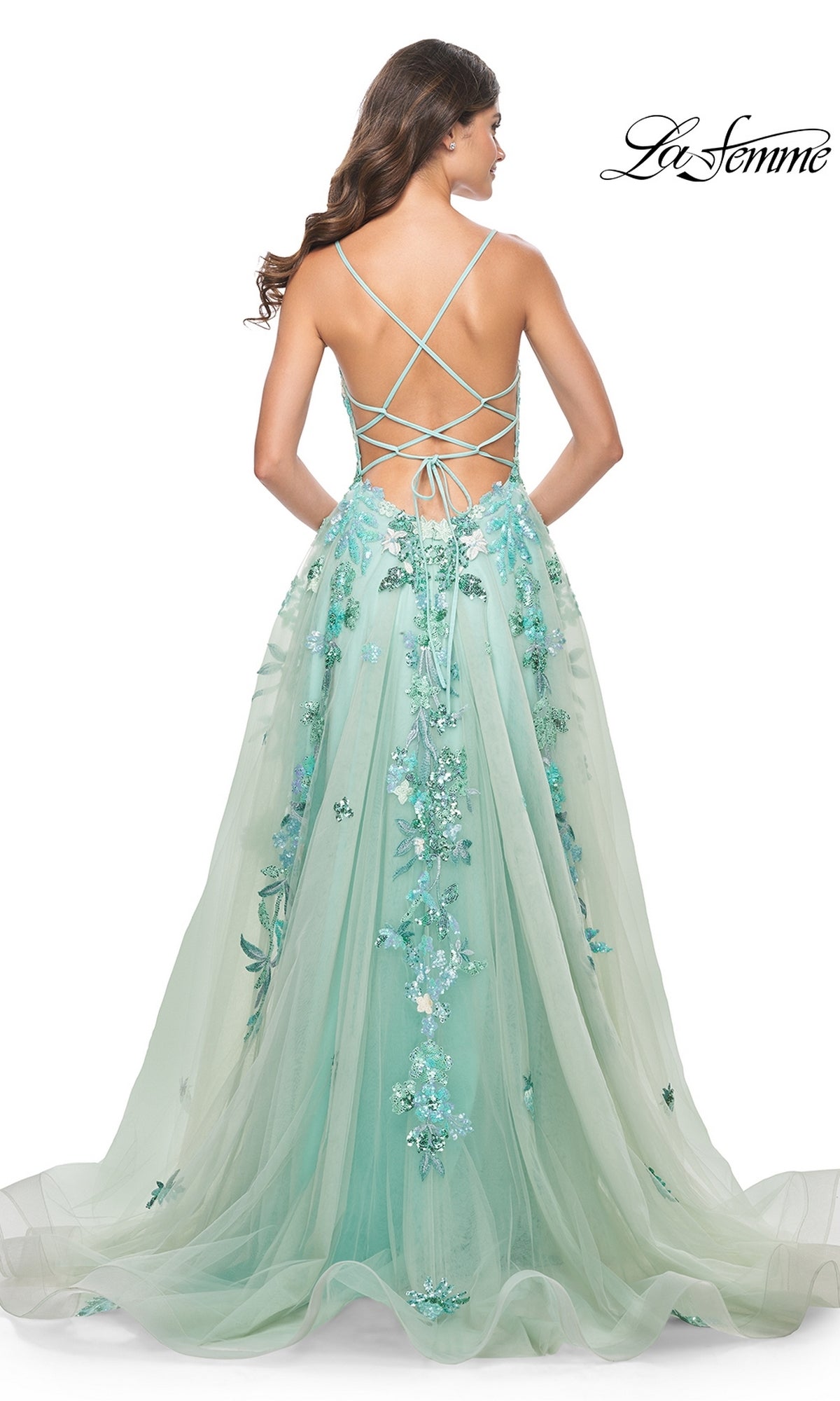 A woman wearing the La Femme Sequin-Print Long Green Prom Dress 32347, featuring a long A-line silhouette and lace-up straps, stands with her back to the camera.